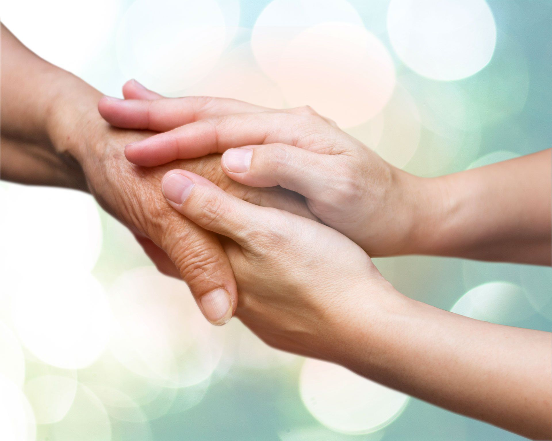 Mani giunte, a offrire conforto o sostegno. Una mano è più anziana, con le rughe.