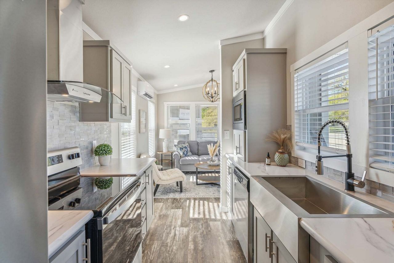 Bright modern kitchen with stainless appliances, white cabinets, and a large window over the sink