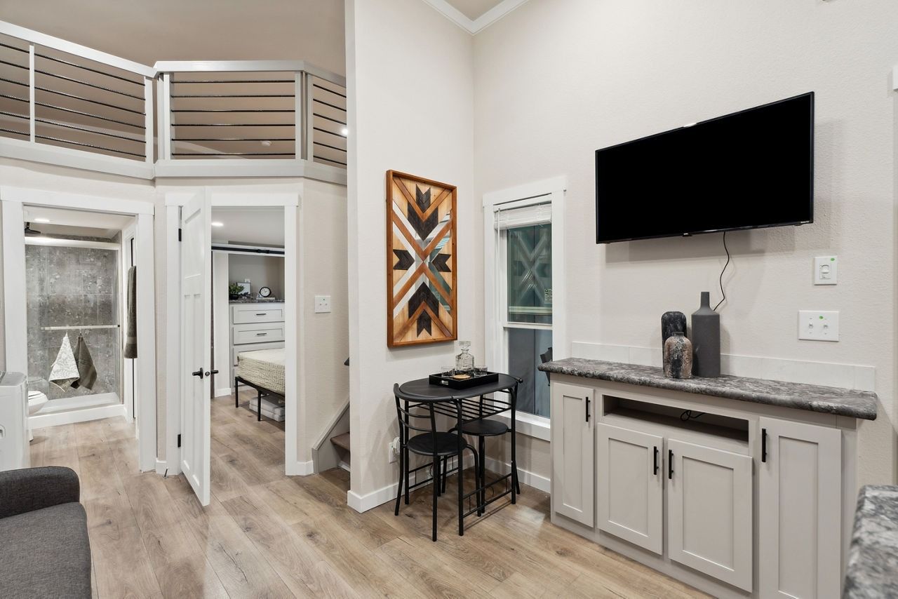 Modern bedroom with loft, bathroom entry, wall-mounted TV, and console table