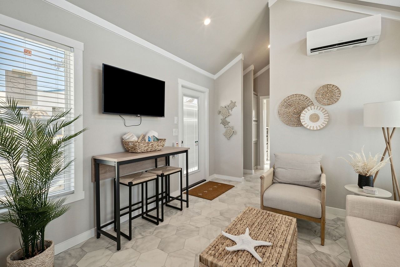 Bright, modern living room with wall-mounted TV, console table, armchair, and neutral decor