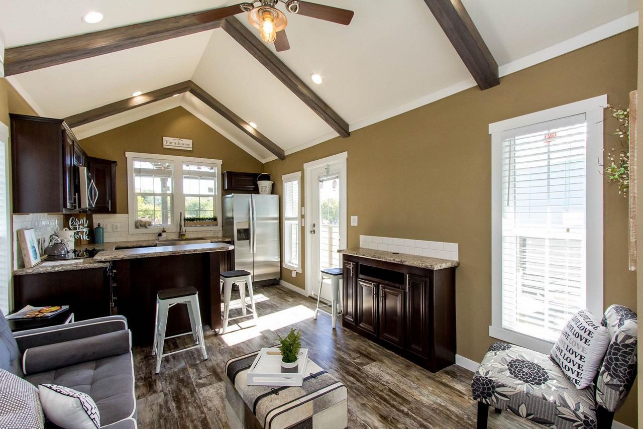 Cozy living room with vaulted ceiling, fireplace, dark wood furniture, and large windows with white blinds
