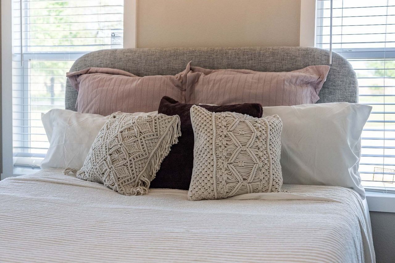 Neatly made bed with layered pillows and white bedding in a bright bedroom