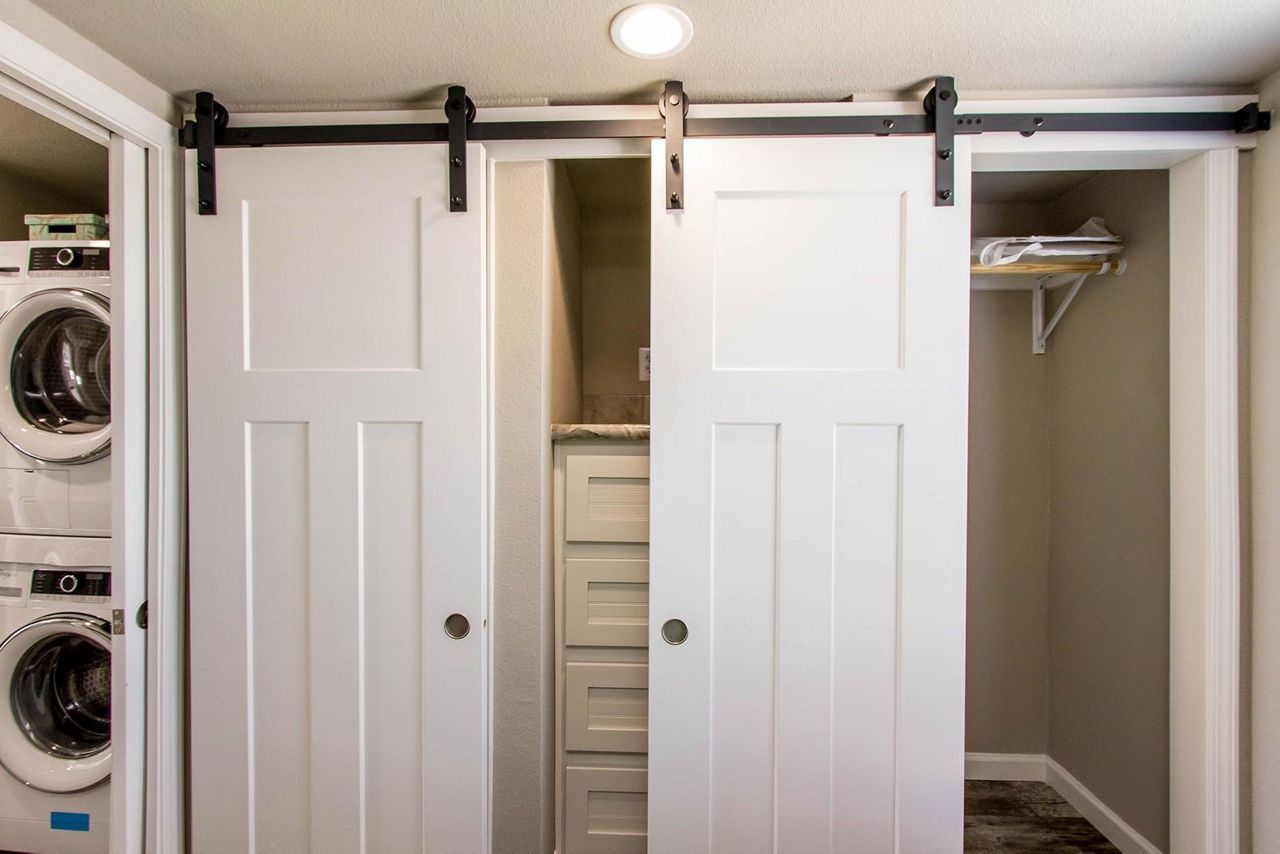 Laundry room with sliding barn doors, washing machines on the left, and a closet on the right.