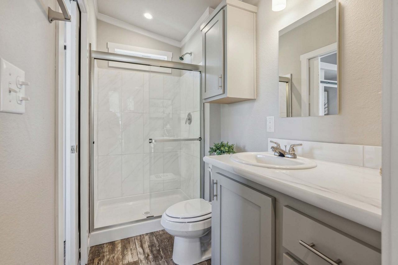 Small bathroom with a shower, toilet, and vanity in light neutral tones.
