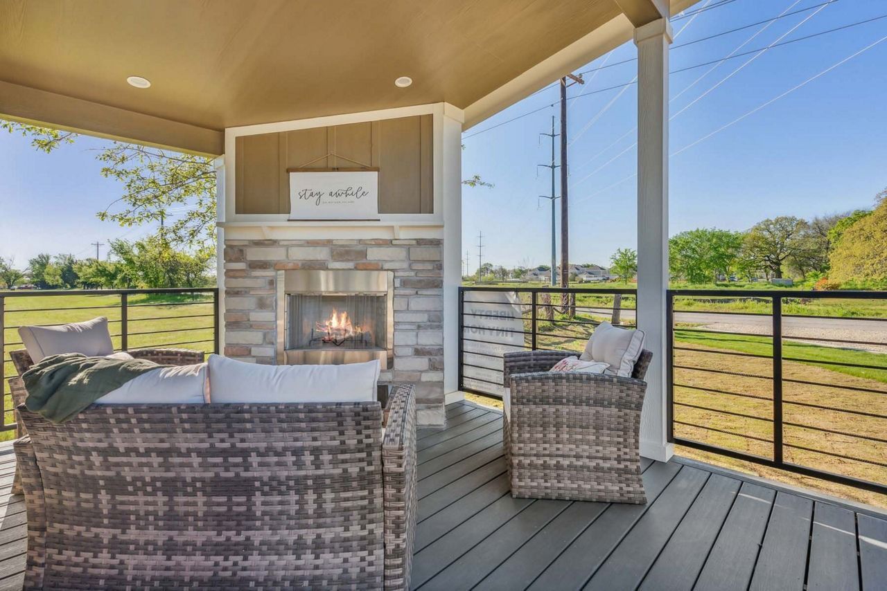 Covered patio with wicker chairs, stone fireplace, and open countryside view