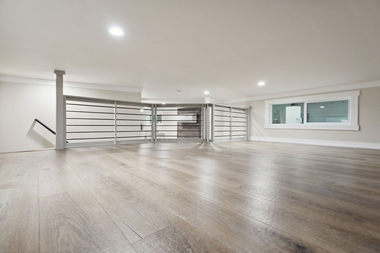 Spacious empty modern room with light wood floors, white walls, and recessed ceiling lights