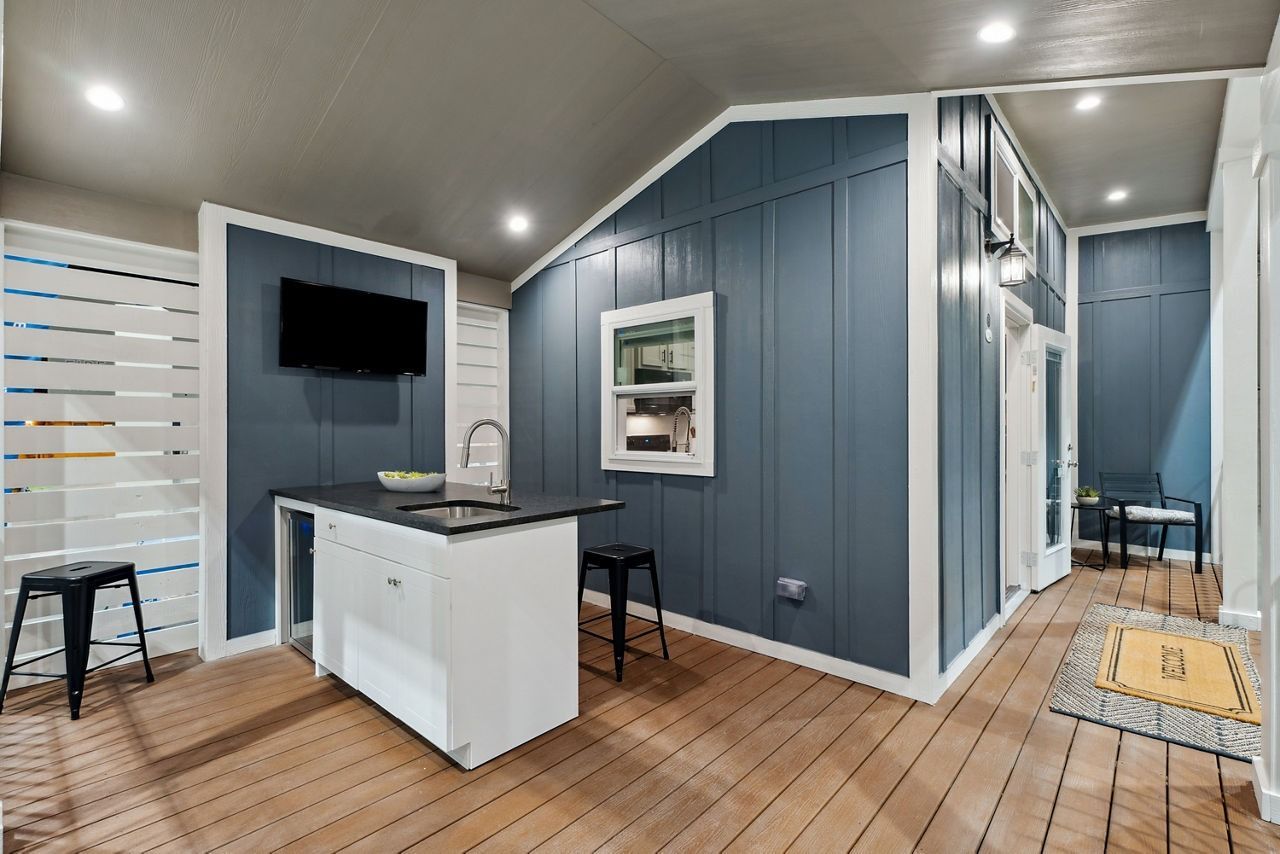 Modern kitchen with blue paneled walls, white island, wood floors, and a hallway beyond