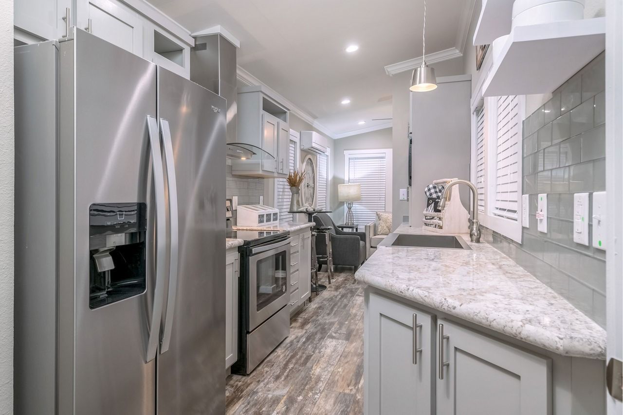 Modern kitchen with stainless steel appliances, white cabinetry, and a granite countertop.