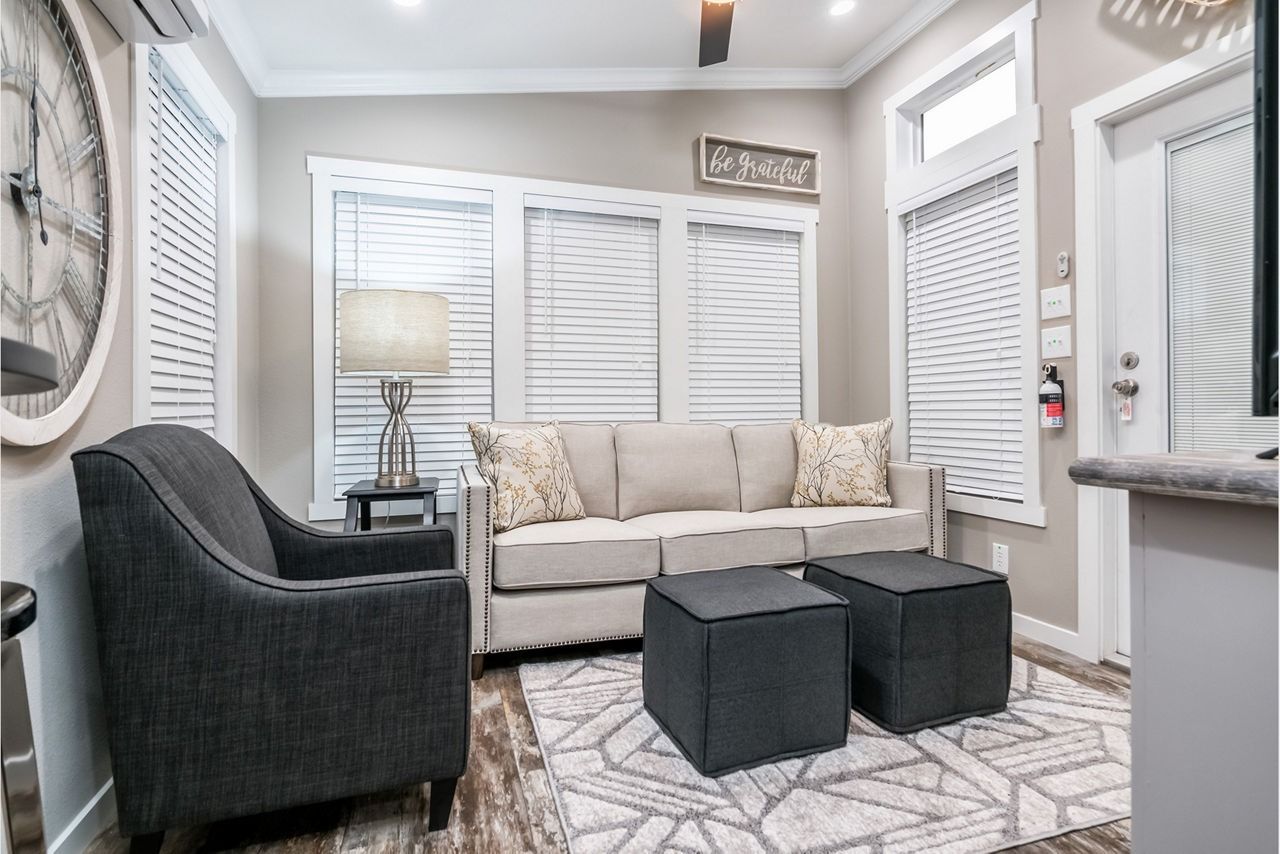 Cozy gray living room with sofa, armchair, floor lamp, ottomans, and patterned rug