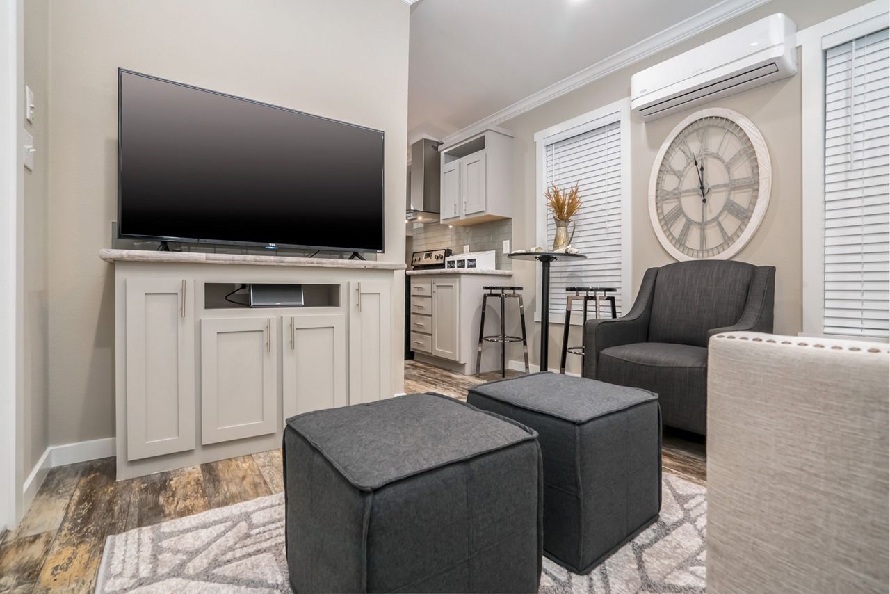 Cozy living room with TV, gray armchair, ottoman cubes, and wall decor in neutral tones