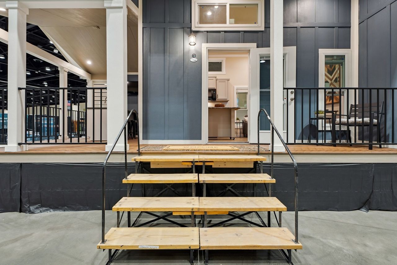 Front porch with wooden steps, black railings, and a blue-gray house entrance at dusk