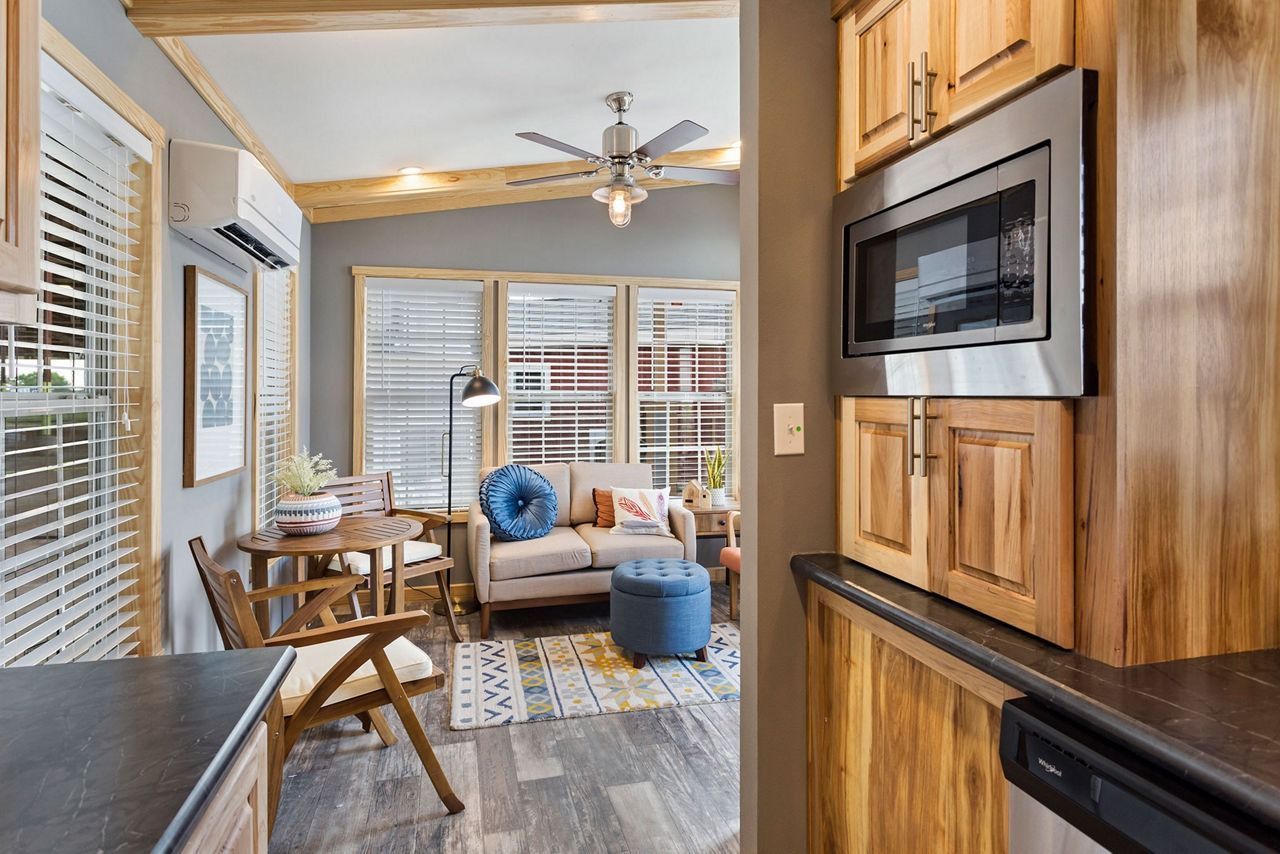 Cozy modern living room with wood accents, sofa, blue ottoman, and a wall-mounted microwave.