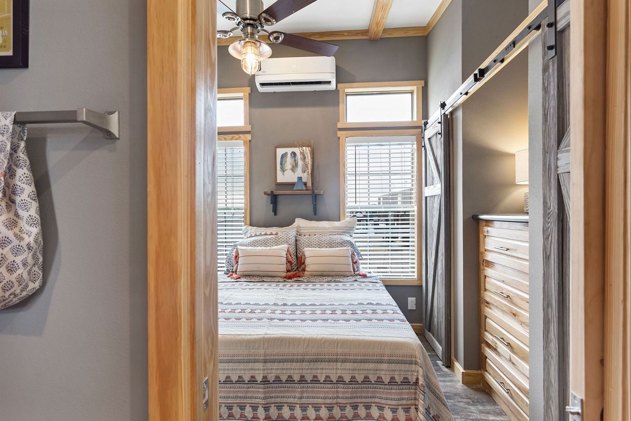 Small bedroom with a bed, ceiling fan, window, and closet shelving.
