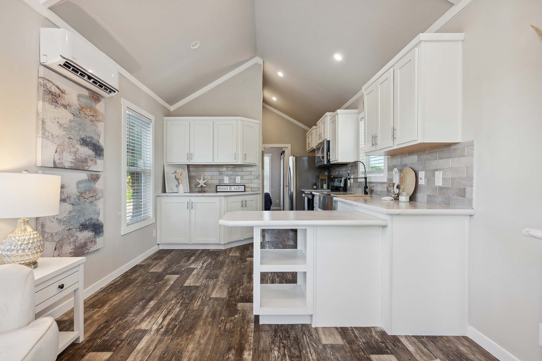 Bright modern kitchen with white cabinets, stainless appliances, and wood-look flooring