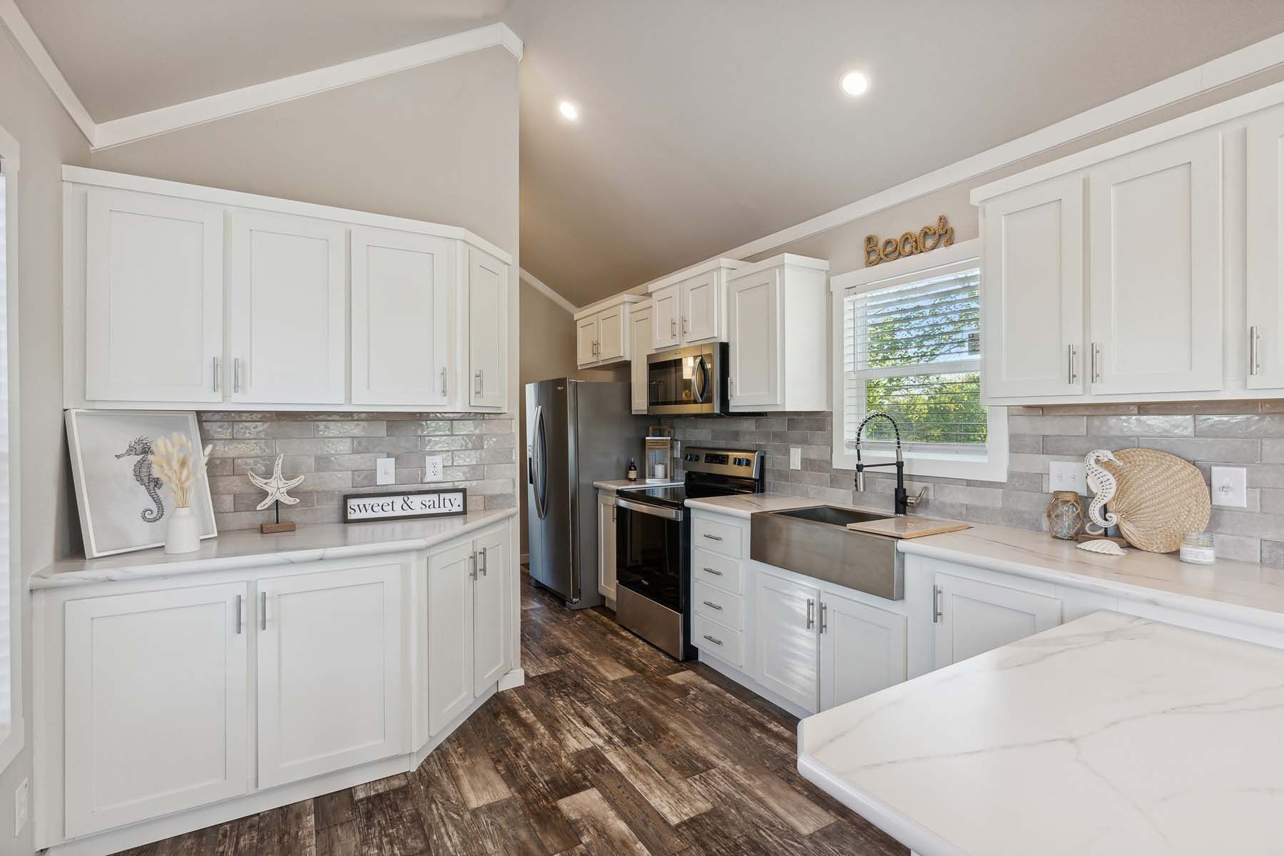 Bright modern kitchen with white cabinets, stainless appliances, and a window over the sink
