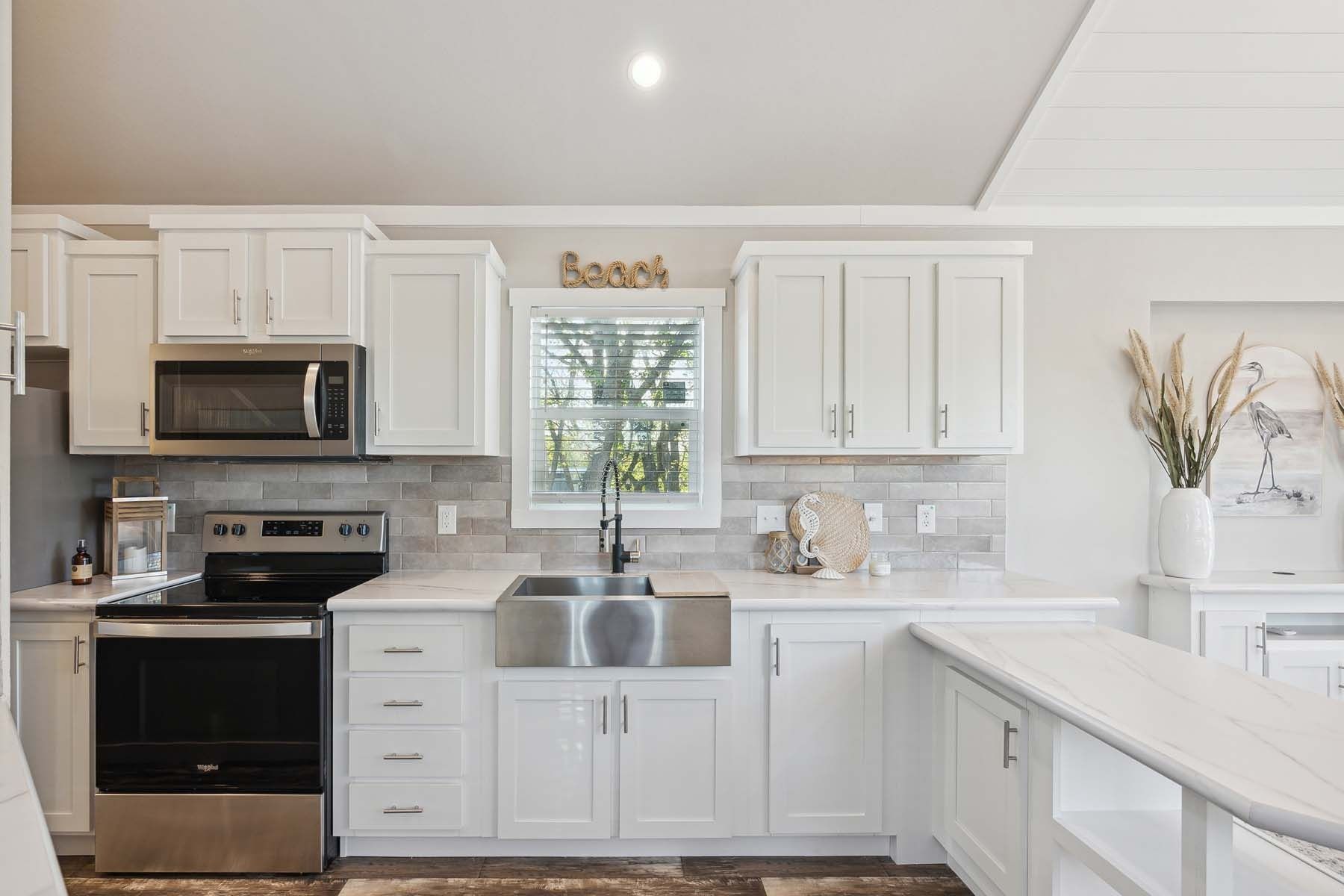 Bright white kitchen with stainless appliances, farmhouse sink, and large island countertop