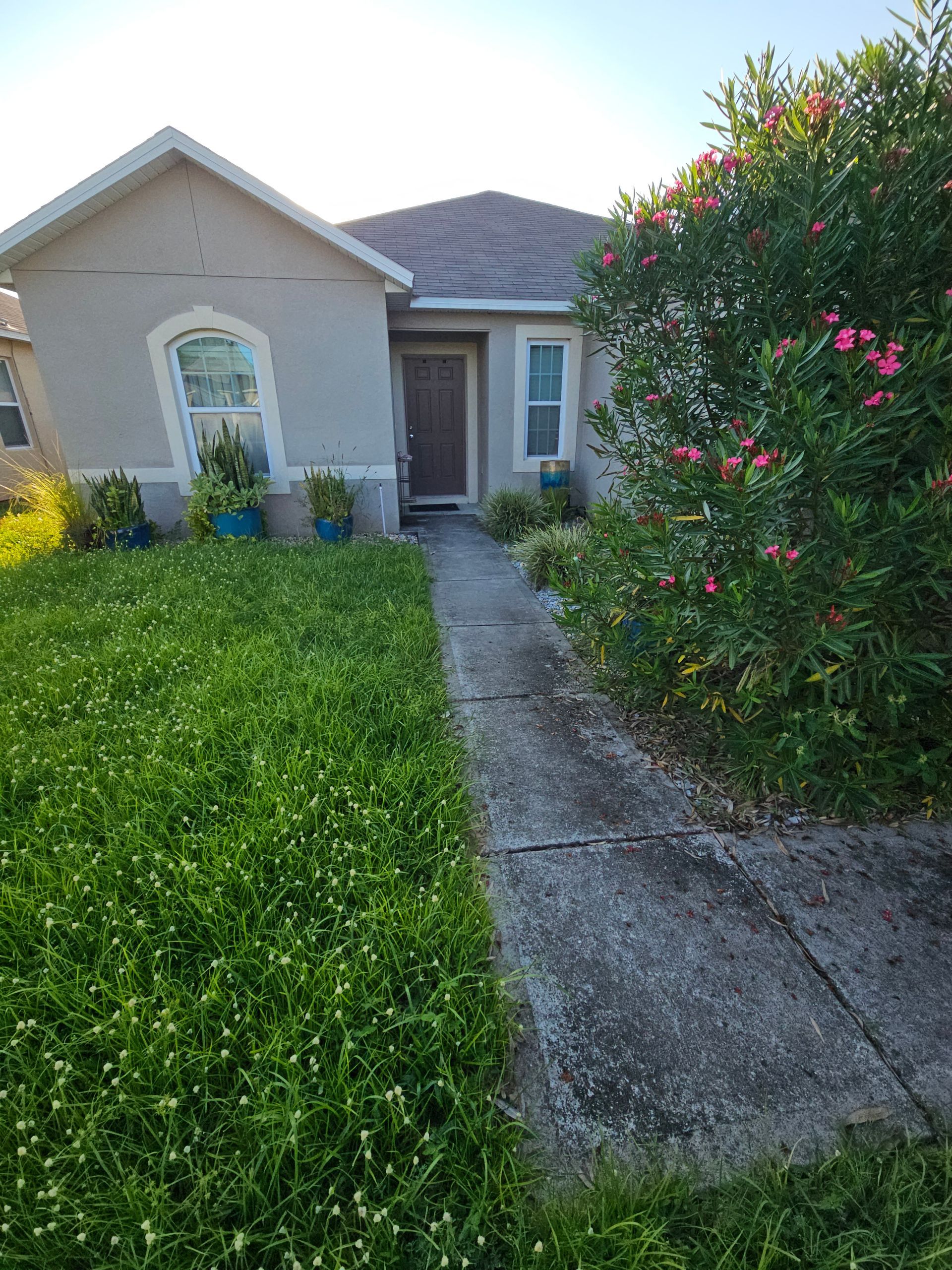 A large white house with a concrete driveway in front of it.