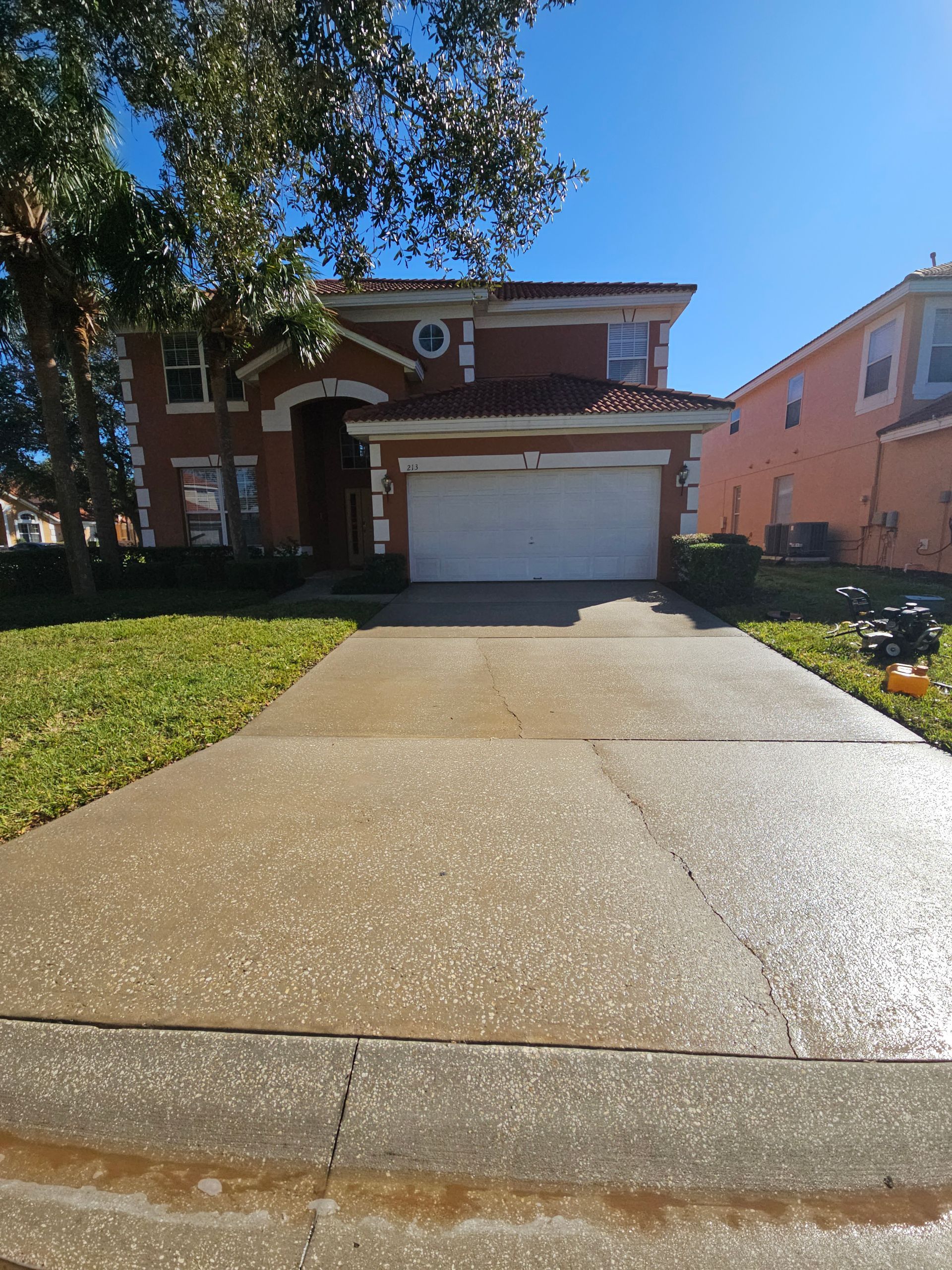 A black van is parked in front of a house next to a lush green lawn.