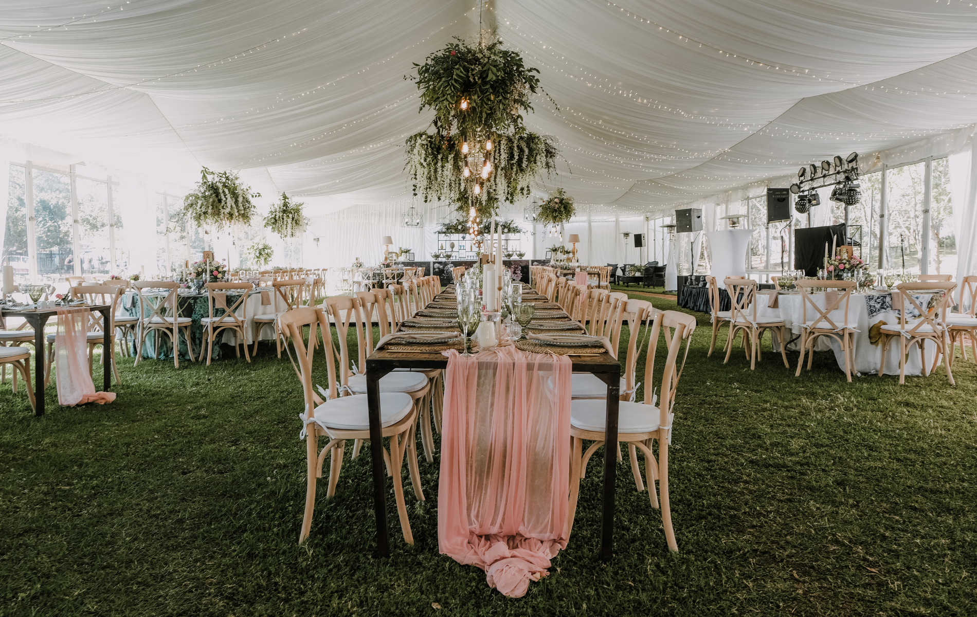 A large tent with tables and chairs set up for a wedding reception.