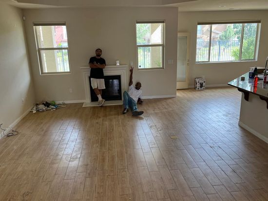 A man is standing next to a fireplace in an empty living room.