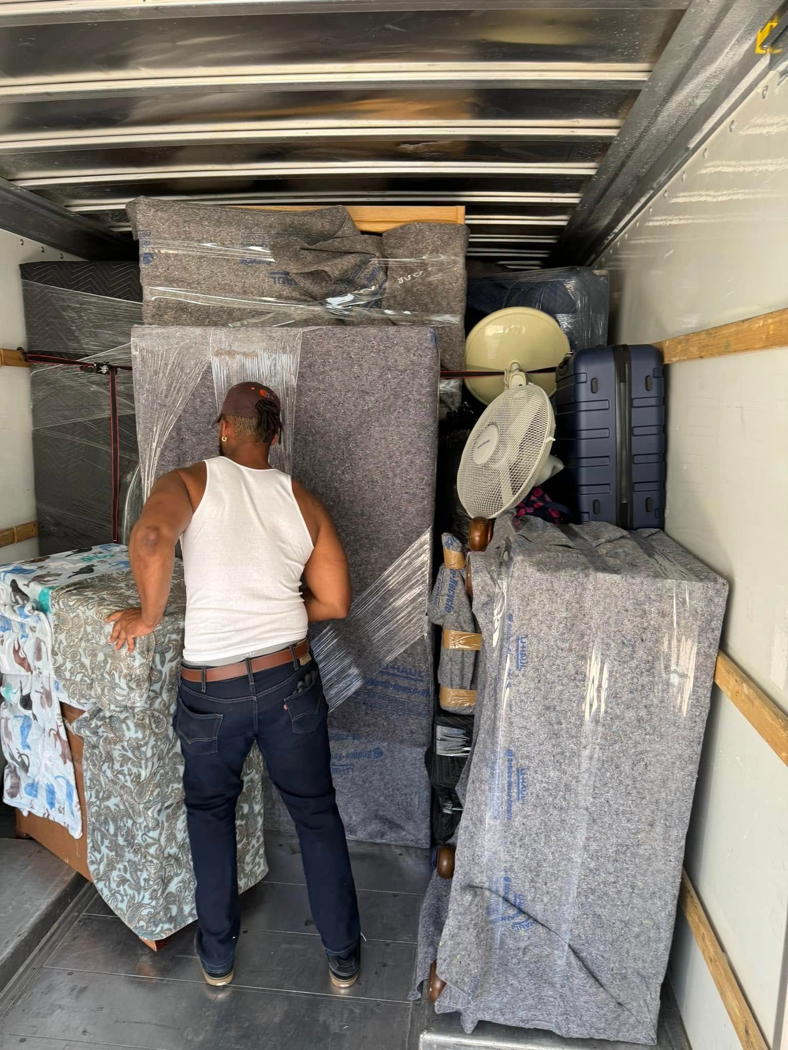A man is standing in the back of a moving truck.