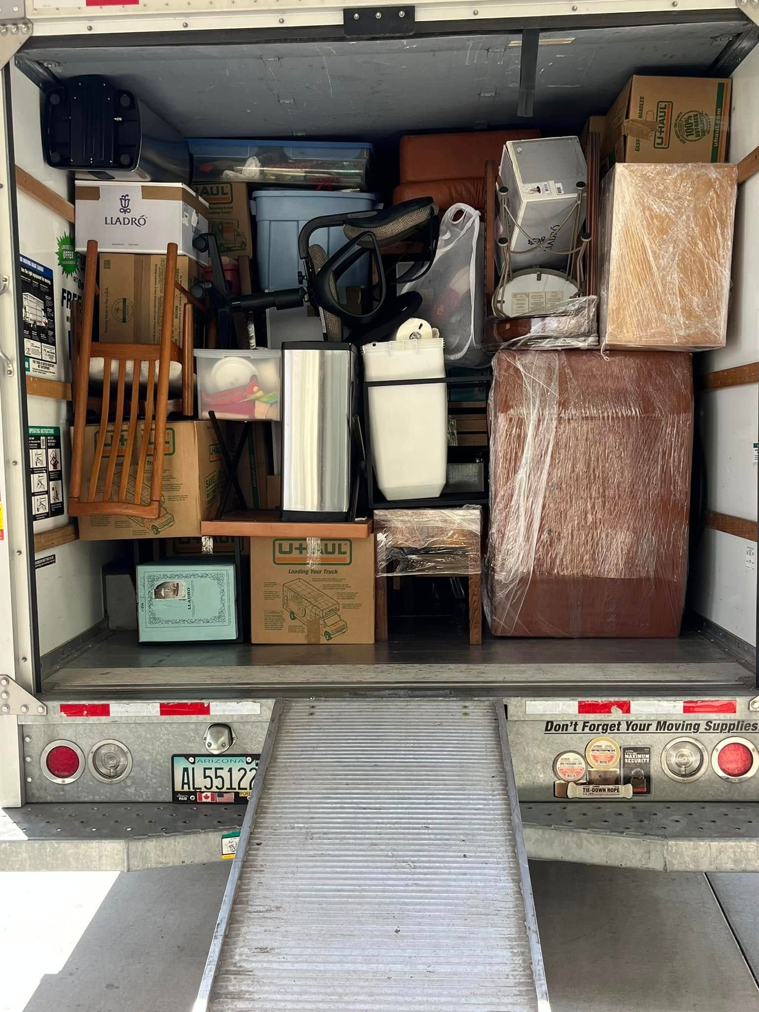 The back of a moving truck filled with furniture and boxes.