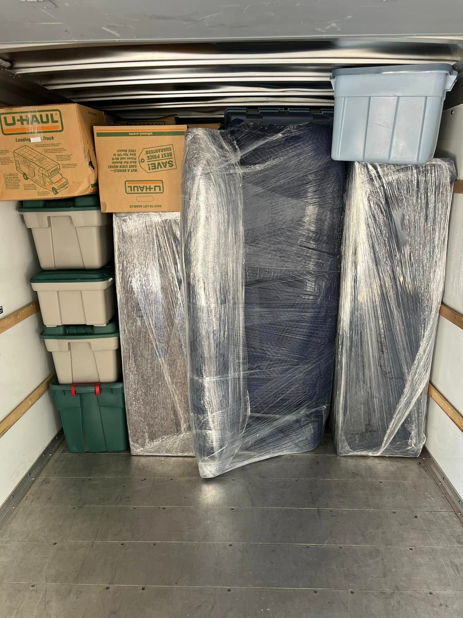 A moving truck filled with boxes and a mattress.
