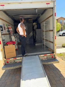 A man is standing in the back of a moving truck.
