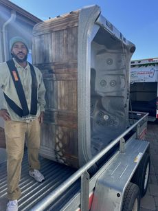 A man is standing next to a hot tub on a trailer.