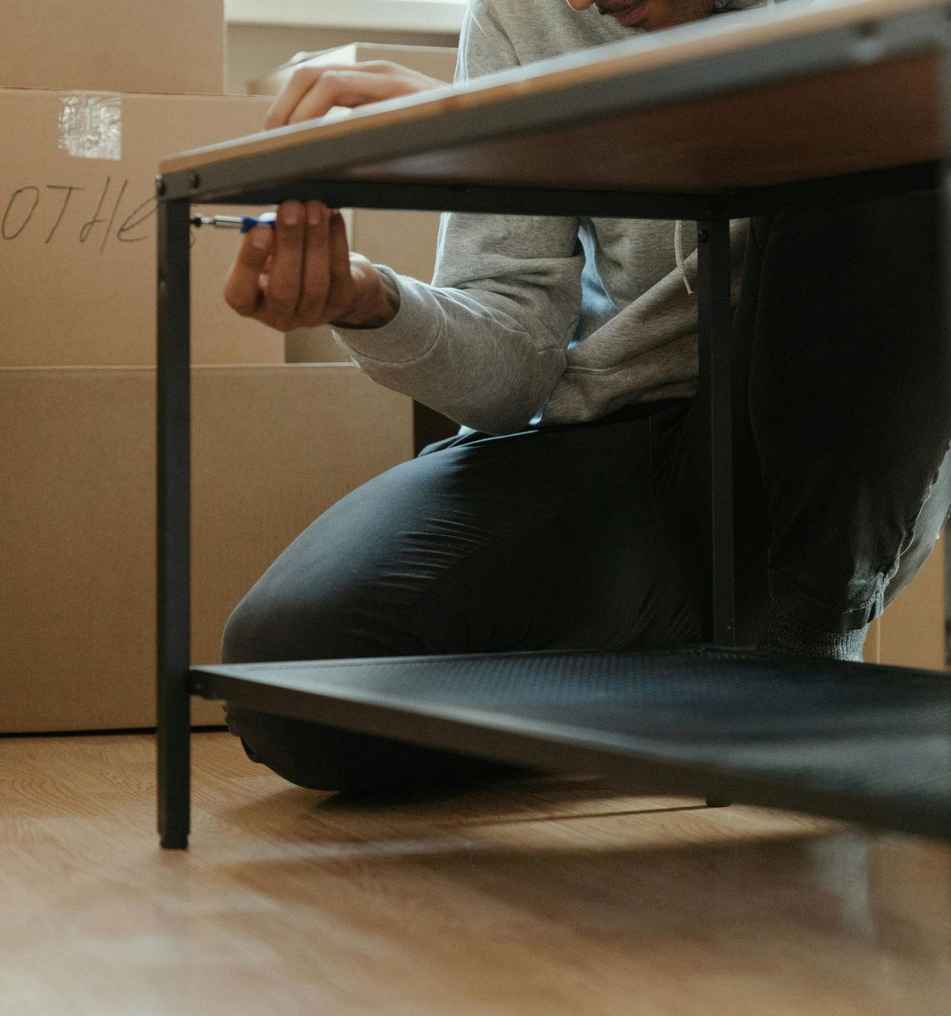 A person is kneeling under a table with the word othe written on it
