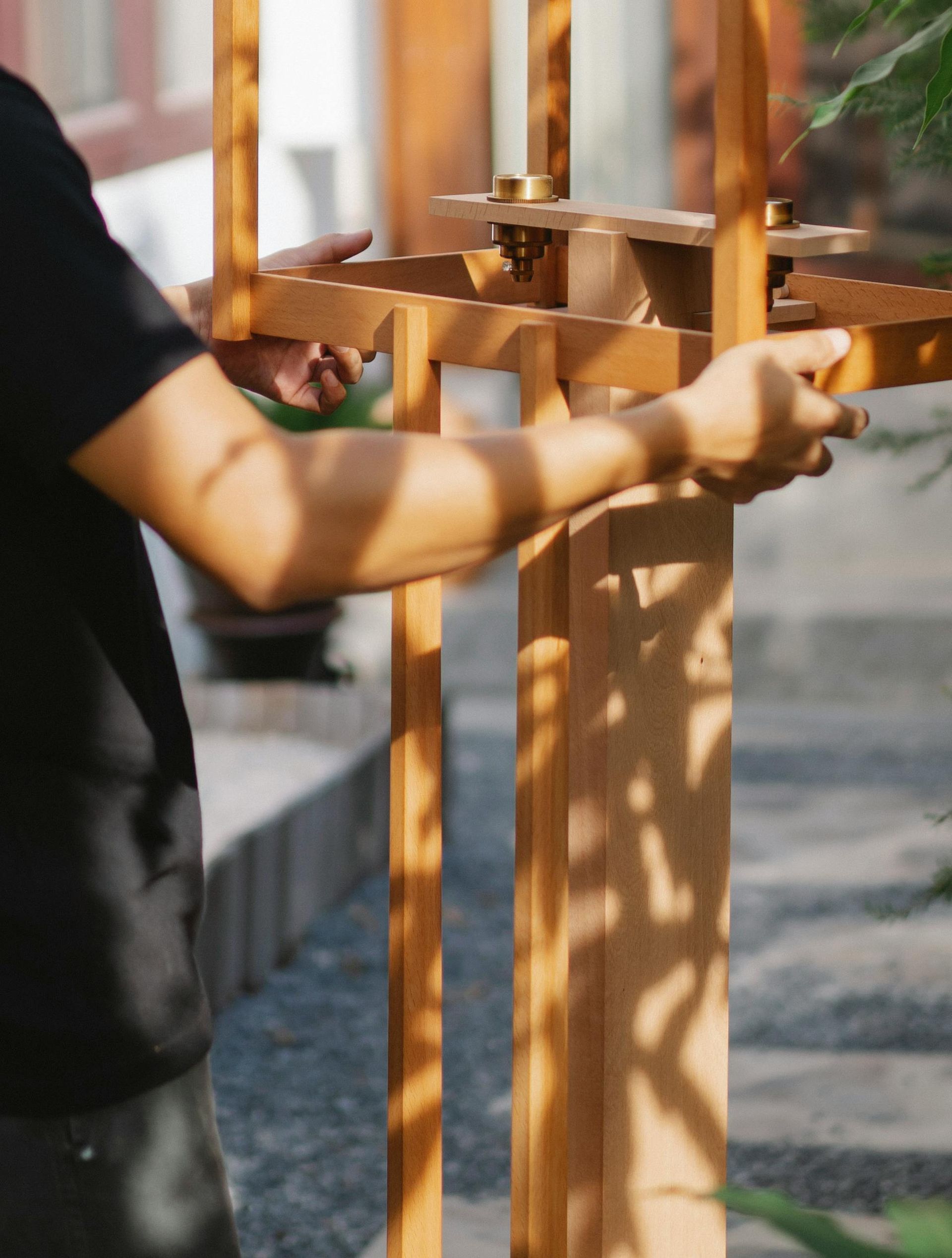 A man in a black shirt is working on a wooden fence