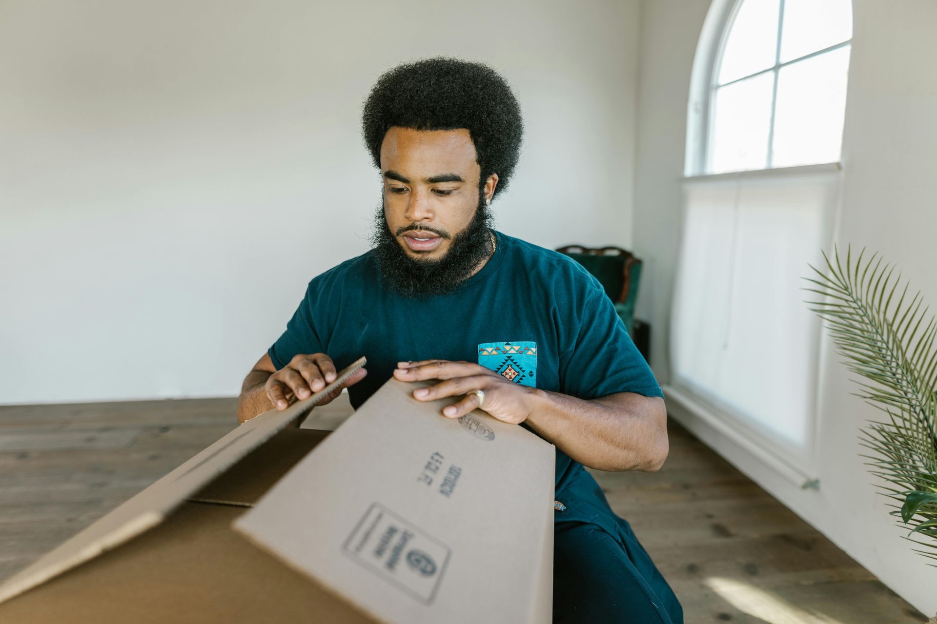 A man is sitting on the floor holding a cardboard box.