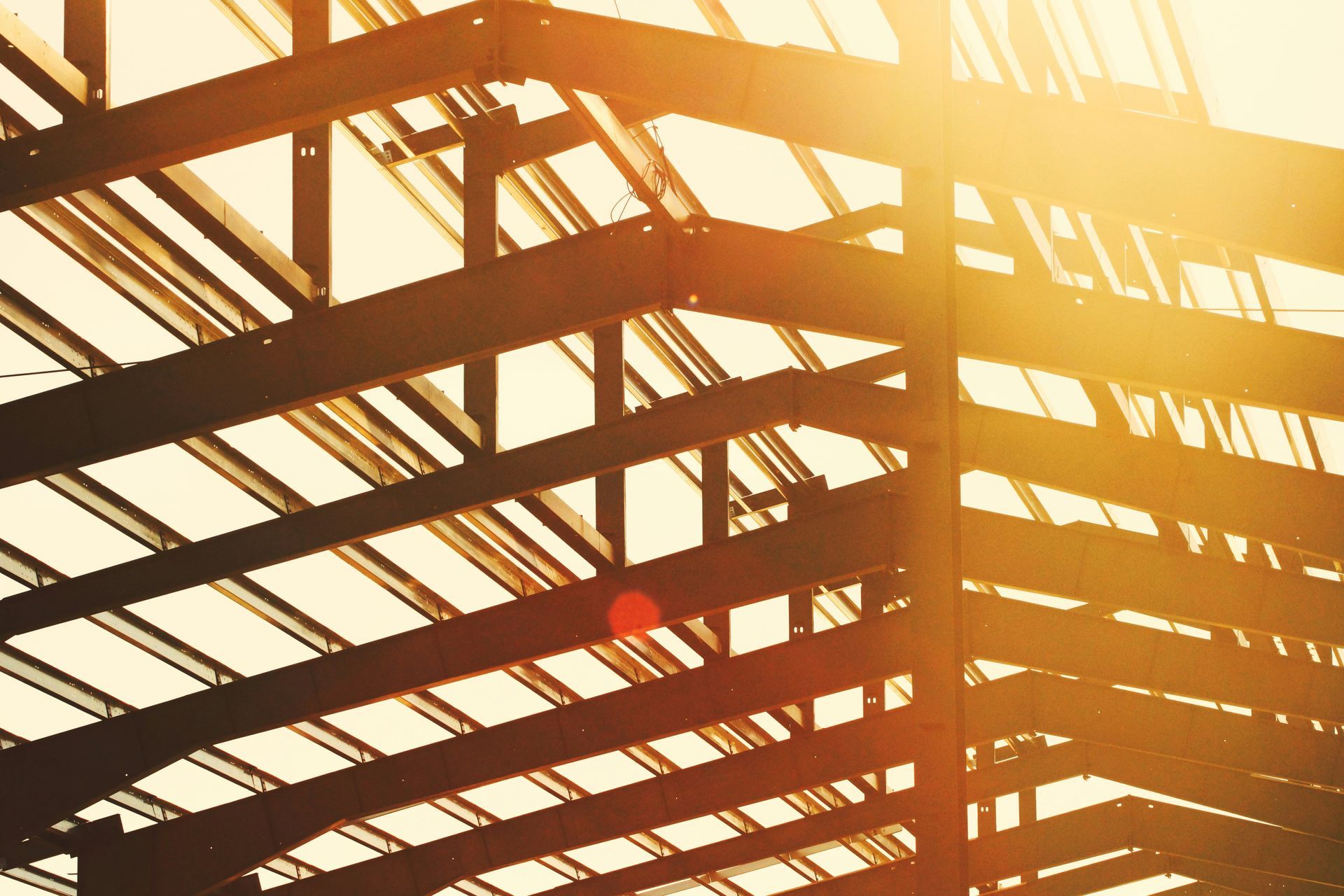Steel beams of a building frame silhouetted by bright sunlight.