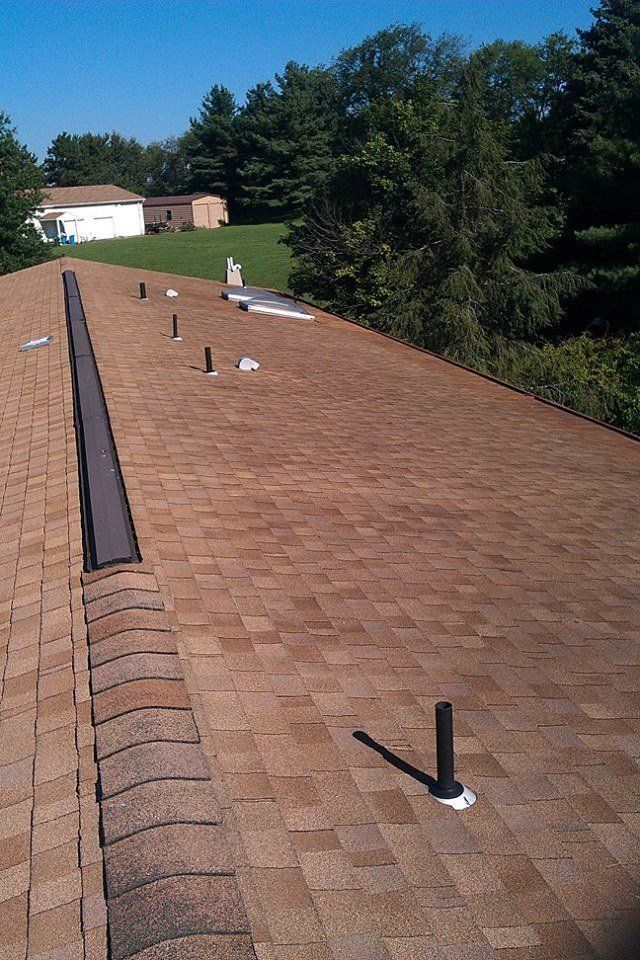 A roof with a lot of shingles and trees in the background