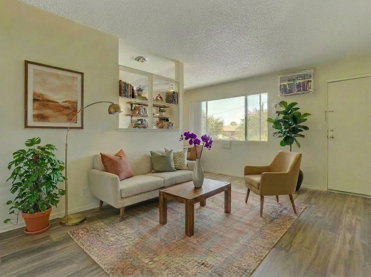Cozy living room with beige sofa, two chairs, coffee table, plants, wall art, and a bright window