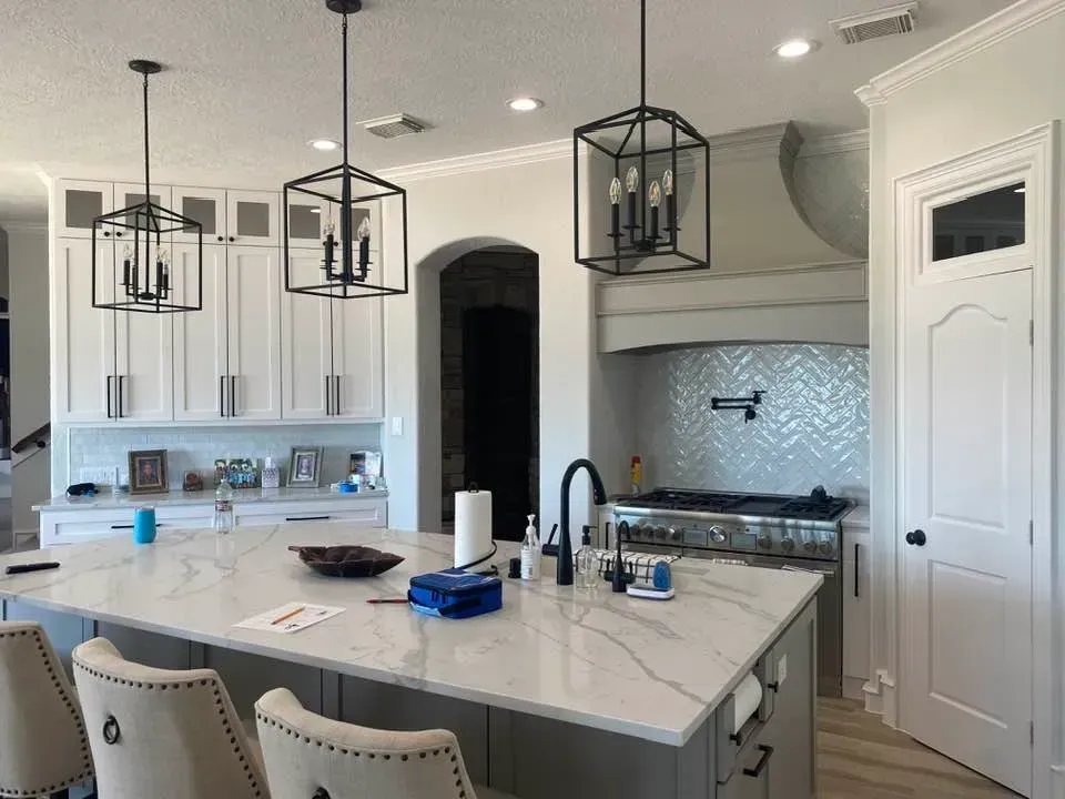 A kitchen with white cabinets and a large island in the middle.