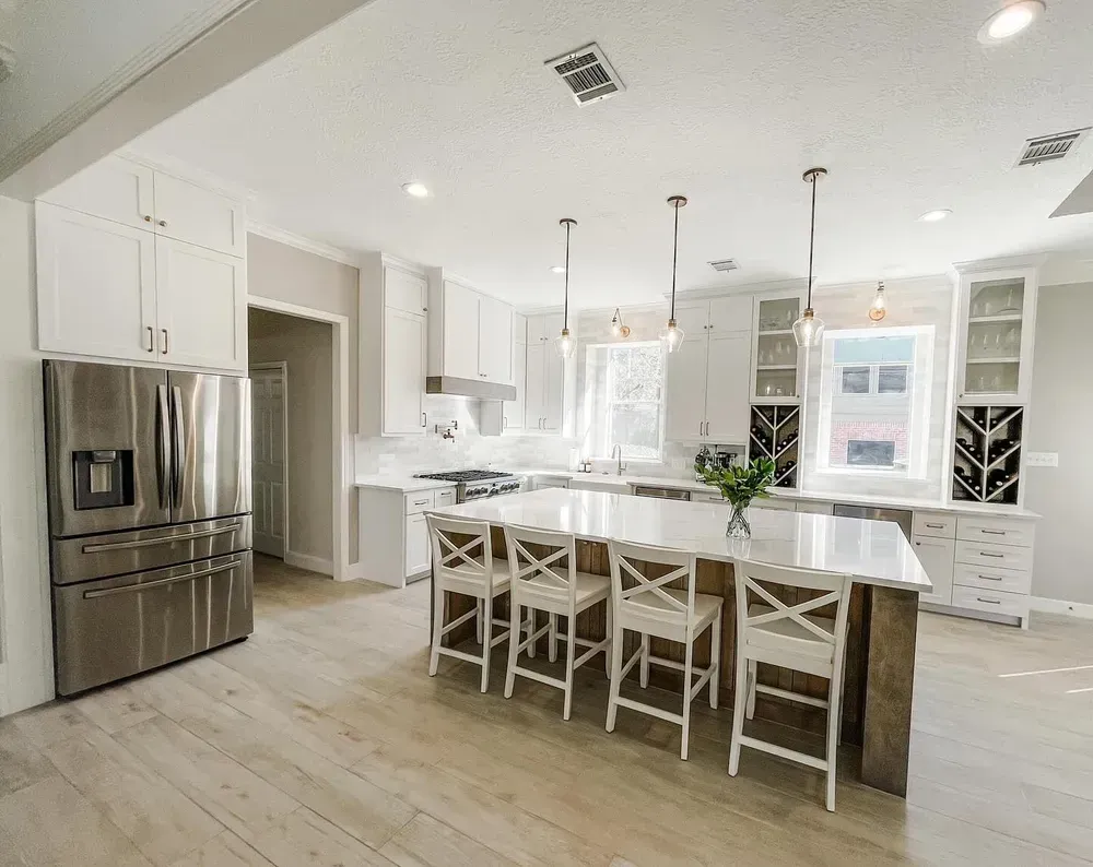A kitchen with white cabinets , stainless steel appliances , and a large island.