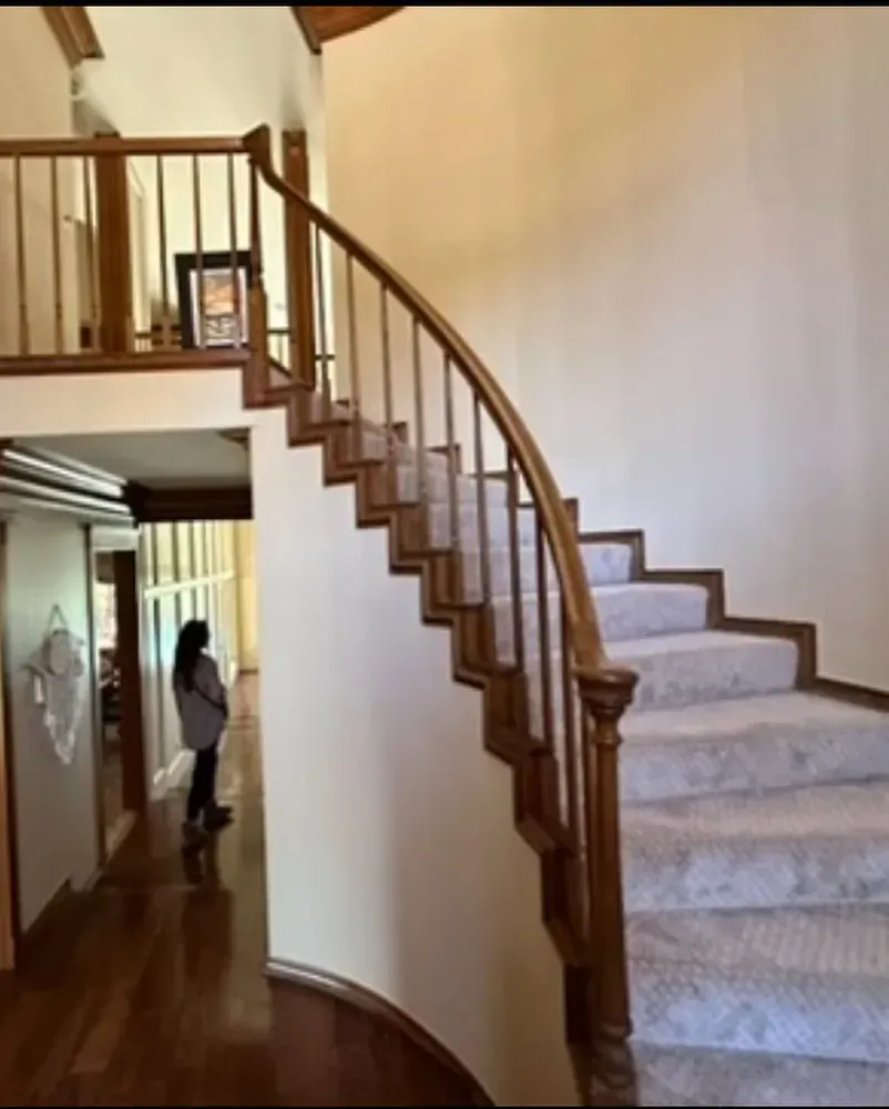 A woman is walking down a spiral staircase in a house