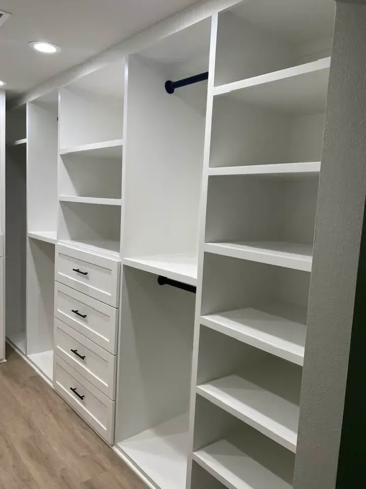 A walk in closet with lots of shelves and drawers.