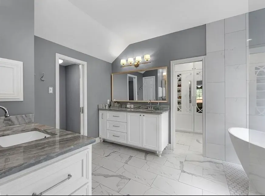 A bathroom with two sinks , a tub , and a mirror.