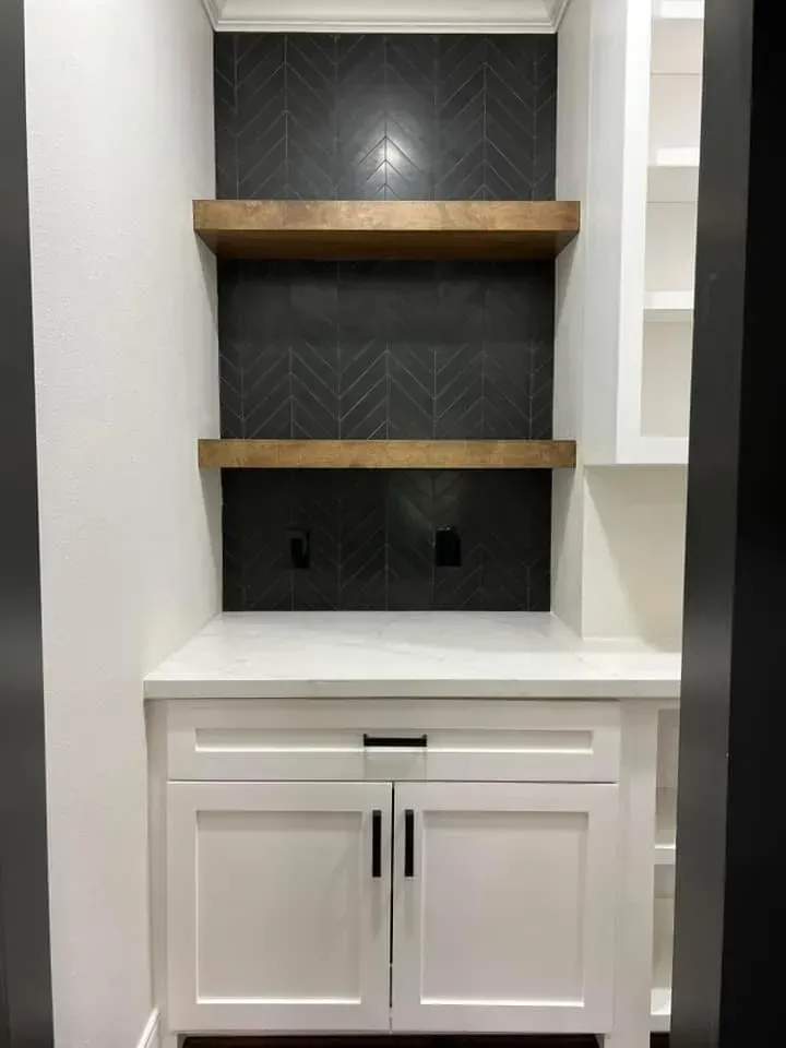 A kitchen with white cabinets and wooden shelves.