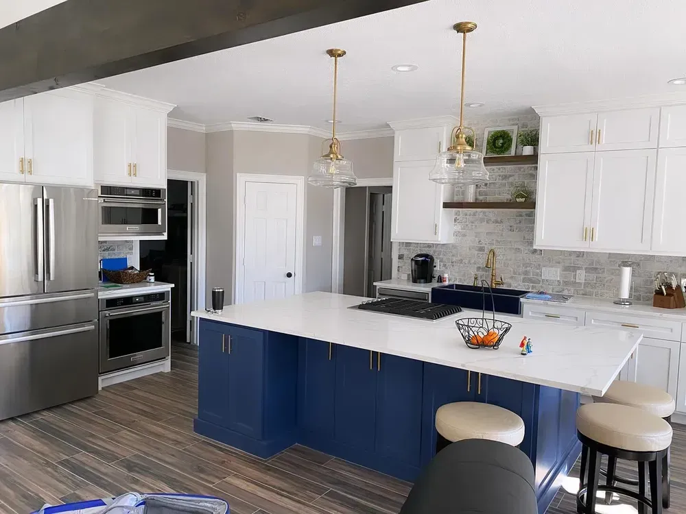 A kitchen with blue cabinets , white counter tops , stainless steel appliances and a large island.