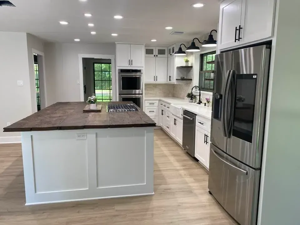 A kitchen with white cabinets , stainless steel appliances , and a large island.