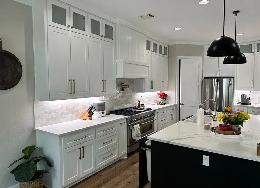 A kitchen with white cabinets , stainless steel appliances , and a large island.