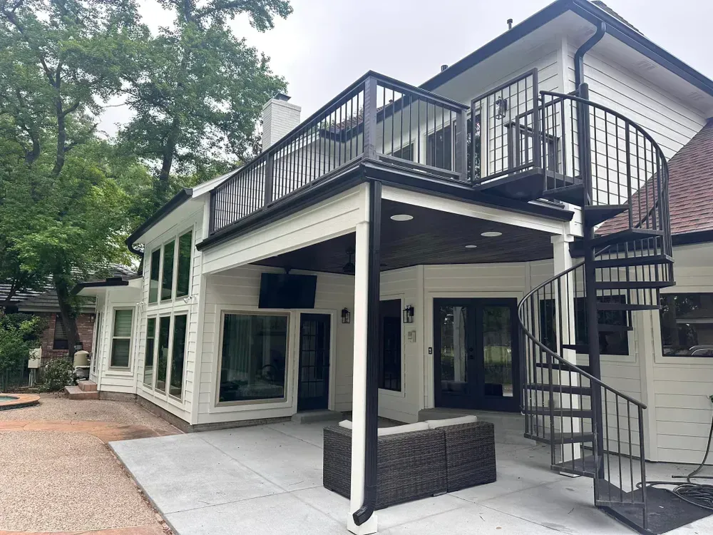 The back of a house with a spiral staircase and a balcony.
