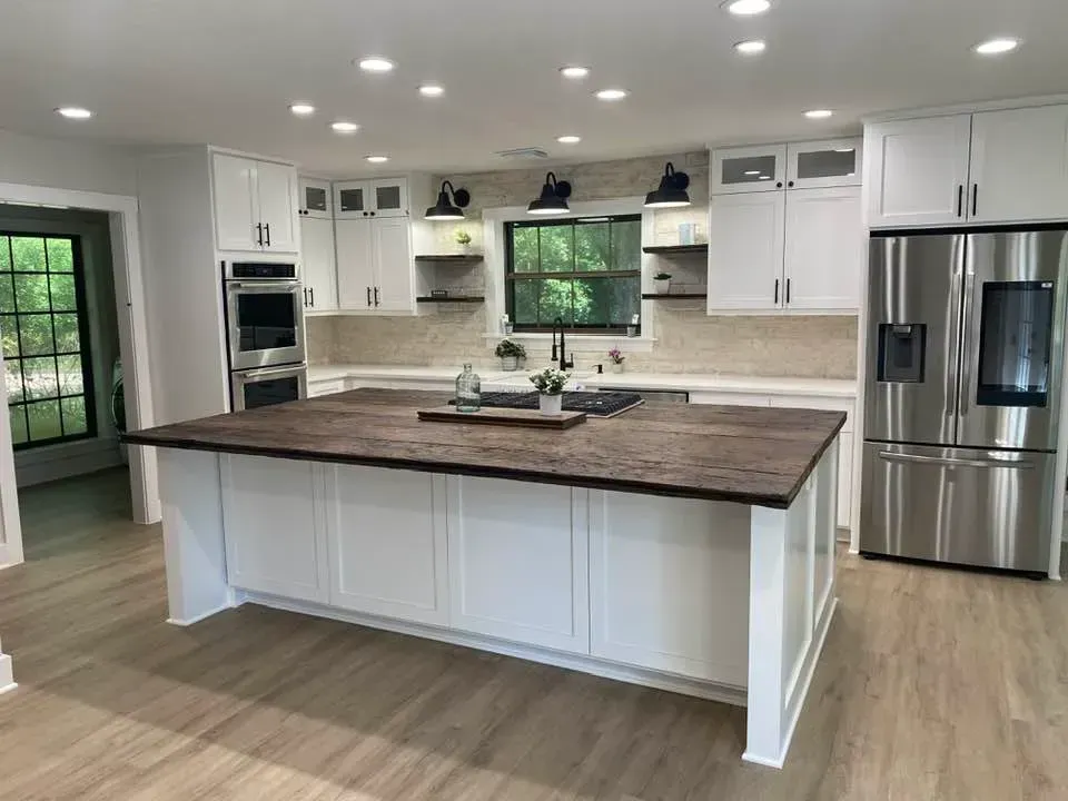 A kitchen with white cabinets , stainless steel appliances , and a large island.