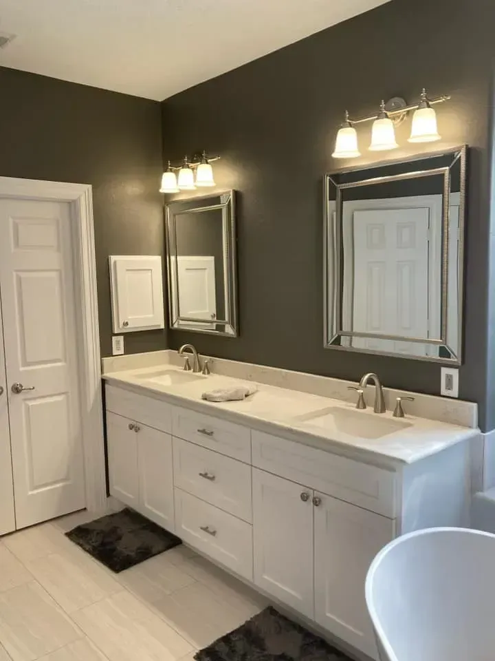 A bathroom with two sinks , two mirrors , and a tub.