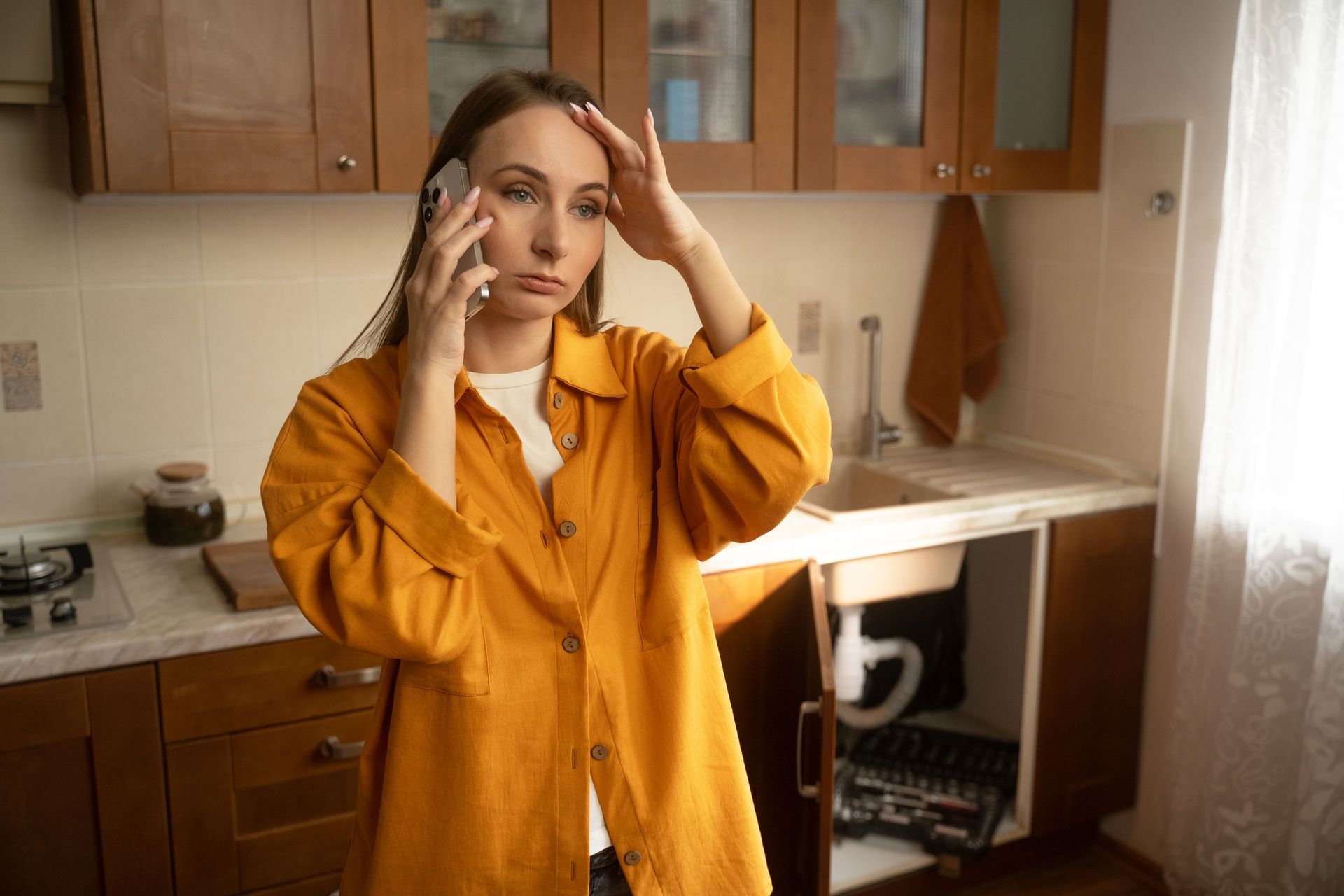 A woman in a yellow shirt stands in her kitchen. A woman in a yellow shirt stands in her kitchen.