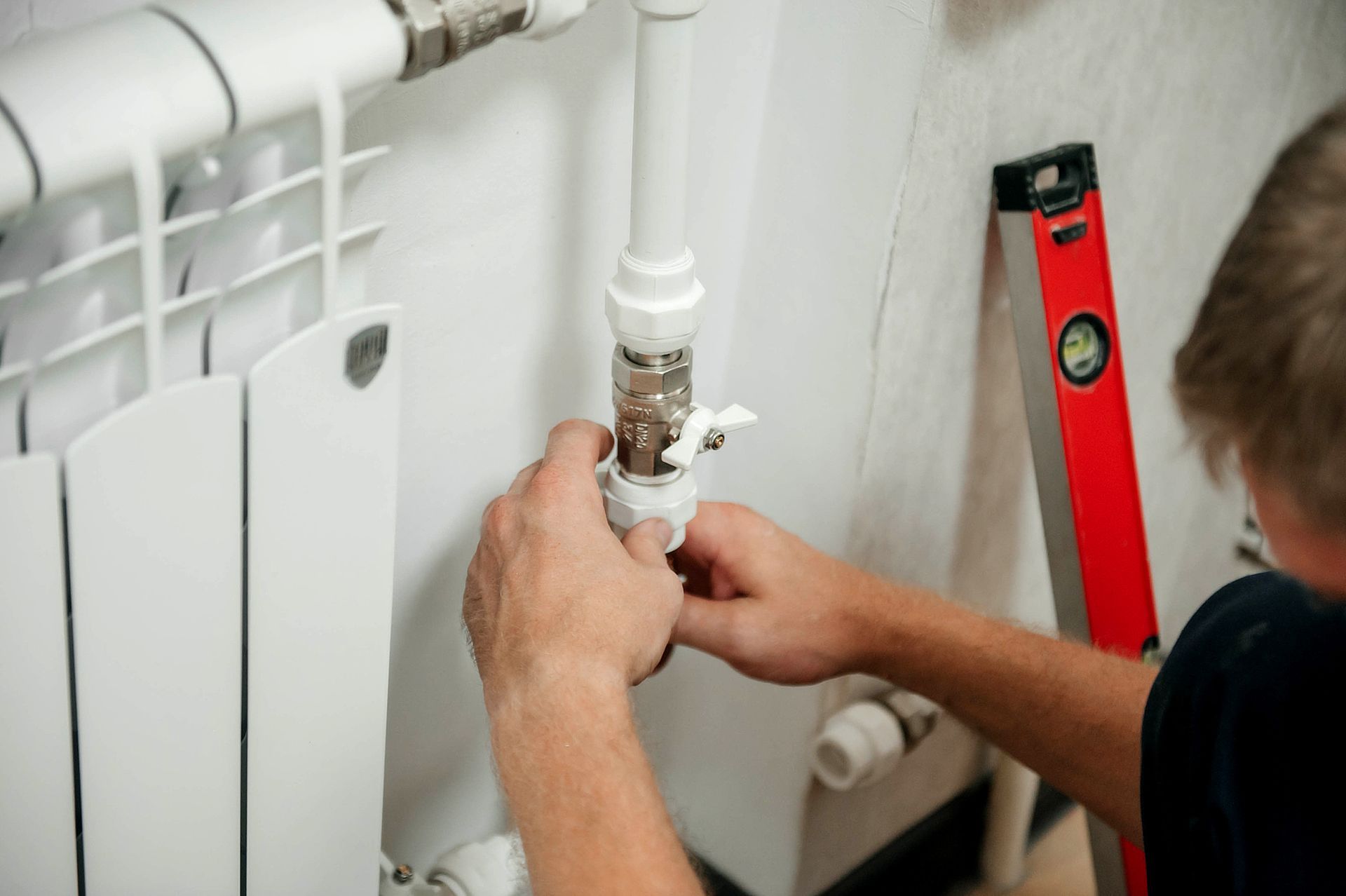A close-up shows a man adjusting a pipe, highlighting essential commercial plumbing repair work.