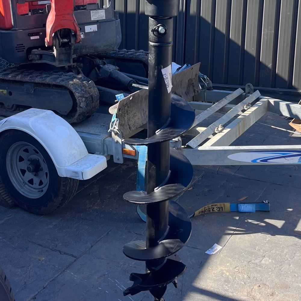 A Large Drill Bit is Sitting on the Ground Next to a Trailer — Garrett's Excavation & Equipment Hire in Sanctuary Point, NSW